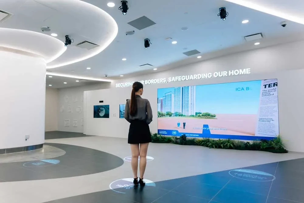 The gallery entrance, a wide white space with a long LED screen under the words Securing our borders, safeguarding our home, and a visitor standing in front of it